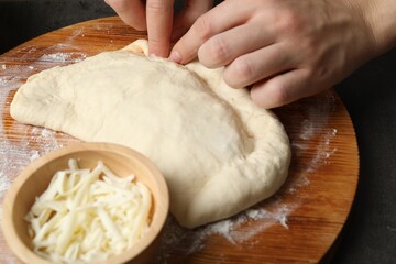 Woman making calzone pizza at grey table, closeup