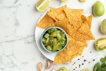 Delicious salsa with nachos on white marble table, flat lay