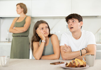 Mom make claims to young couple in home kitchen