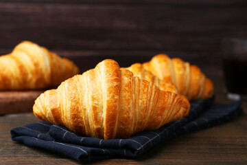 Tasty fresh croissants on wooden table, closeup. Puff pastry