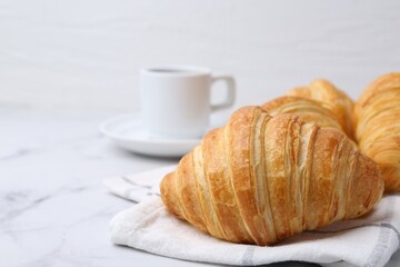 Tasty fresh croissants and cup of drink on white marble table, closeup. Space for text
