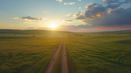 A serene landscape featuring a dirt road leading towards a sunset over green fields.