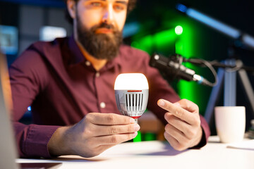 Close up shot of smart light bulb used by tech guru to teach viewers how to do maintenance. Focus...