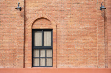 Orange brick wall decorated with arched frame and mirror window inside.