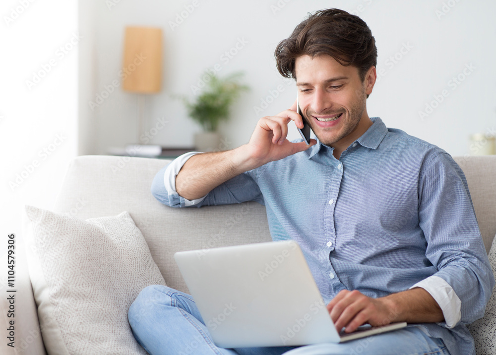 Poster always in touch. successful entrepreneur talking on cellphone working at laptop sitting on sofa at h