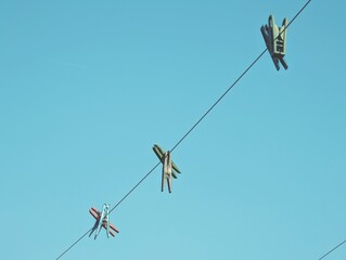  Clothesline with two clothespins against a clear blue sky, creating a minimalist, natural scene....