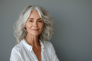 Fototapeta premium Stylish senior woman with grey hair smiling in white shirt, healthy skincare, beauty, dental care, happy elderly model