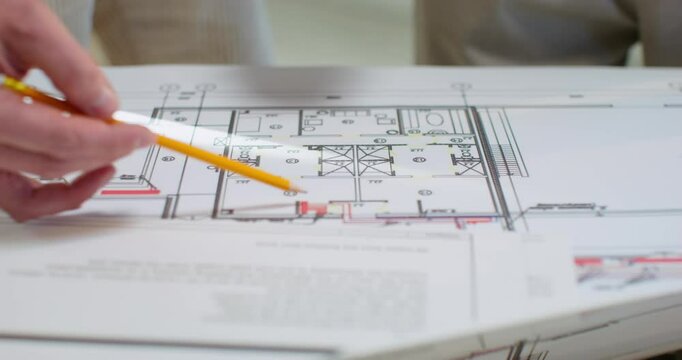 The foreman studies the building plan with the client. Close-up of the plan, unrecognizable persons