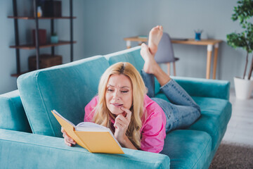 Young woman enjoying leisure with book on cozy sofa in bright daylight