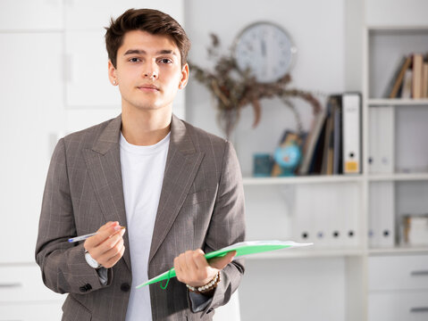 Man office worker holding folder in hands and looking at camera