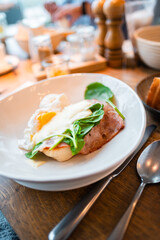 Elegant Brunch Plate Featuring Poached Egg with Ham, Spinach, and Hollandaise Sauce in a Contemporary Setting