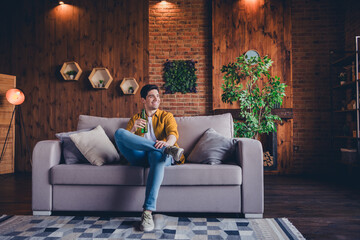 Obraz premium Young man enjoying leisure time indoors on a cozy weekend afternoon in a stylish living room
