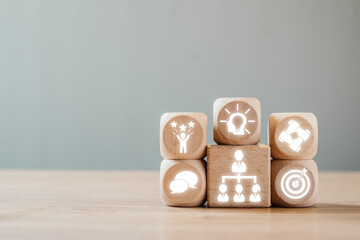 Wooden blocks with icons symbolizing leadership, teamwork, innovation, and success in a business...