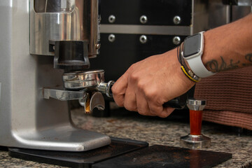 Barista using a coffee grinder, preparing espresso in a coffee shop