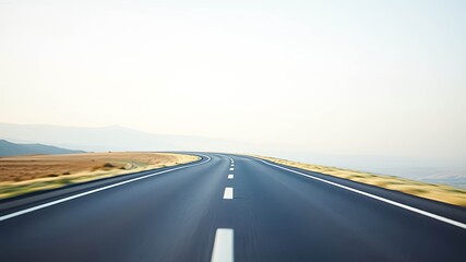 Naklejka premium Asphalt road curving gently through a landscape under a pale sky, leading to an open horizon.