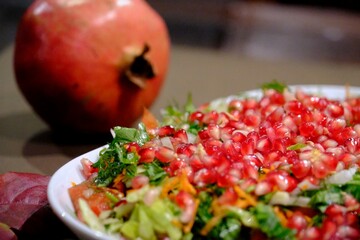 Vitamin-packed winter Christmas salad decorated with pomegranate seeds. Christmas salad with pomegranate, carrots and dill on a white plate, close-up. New Year's table special salad.
