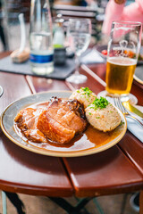 Delicious Plate of Roast Pork with Dumplings and Beer in a Cozy Restaurant Setting