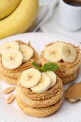 Tasty sandwiches with peanut butter, banana, mint and spoon on table, closeup