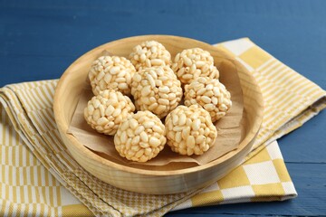 Tasty puffed rice balls on blue wooden table, closeup