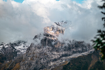 Dramatic Mountain Peak Shrouded in Mist with Clouds and Snowy Summit Revealing Rugged Beauty of Nature Landscape