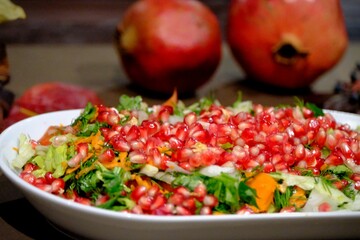 Vitamin-packed winter Christmas salad decorated with pomegranate seeds. Christmas salad with pomegranate, carrots and dill on a white plate, close-up. New Year's table special salad.
