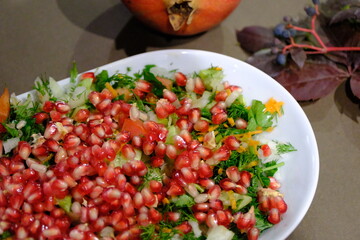 Vitamin-packed winter Christmas salad decorated with pomegranate seeds. Christmas salad with pomegranate, carrots and dill on a white plate, close-up. New Year's table special salad.

