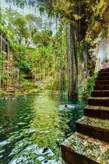 Ik Kil Cenote, Mexico - January 2, 2022 Chichen Itza, Enchanting cenote featuring crystal-clear water, hanging vines, and lush greenery, with a stone staircase leading to the natural pool High-quality