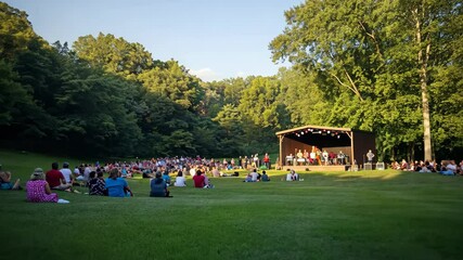 Outdoor music concert attracts large crowd in a serene park setting during a summer evening
