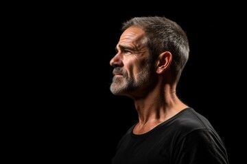 Obraz premium profile portrait of a mature man with a thoughtful expression against a dark background