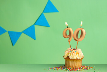 Birthday card with number 90 candle - Cupcake on a green background with blue pennants.