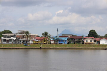 Obraz premium wide-angle urban landscape lone bright blue building on the far shore of a river with towering mountain peak behind in the distance