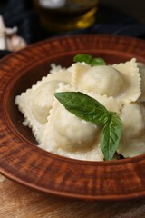 Delicious ravioli with cheese and basil served on wooden table, closeup
