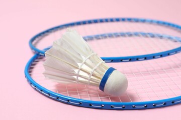 Badminton rackets and white badminton shuttlecock on color background
