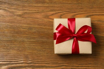 Beautiful gift box tied with bow on wooden background 