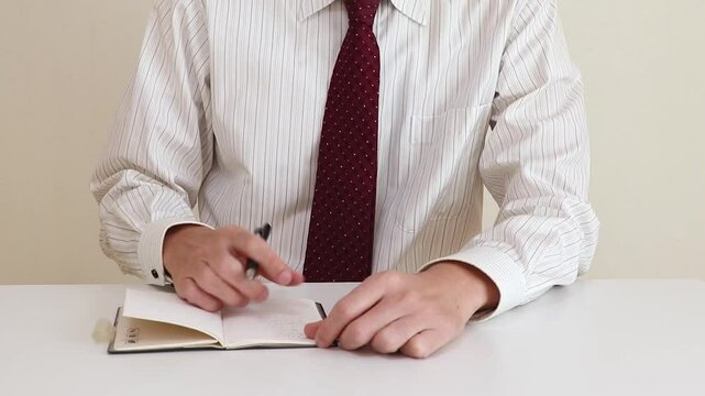 手帳を見返してメモを確認する男性