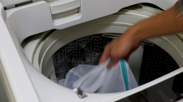 洗濯機の蓋を開けて洗い終わった洗濯物を取り出す