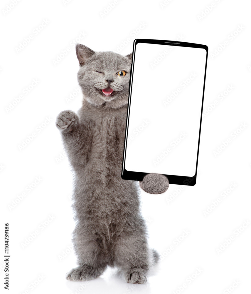 Aufkleber Winking cat holds big smartphone with white blank screen in it paw, showing close to camera. isolated on white background