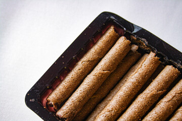 Chocolate wafer rolls in a plastic packaging on white background