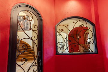 Elegant entryway with ornate metalwork and vibrant red walls in a cozy home