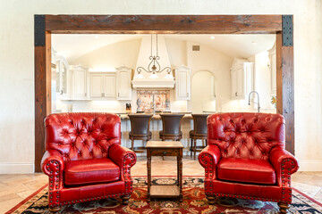 Cozy living area with elegant red chairs and a spacious kitchen in view