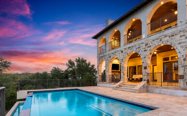 Luxurious stone villa with pool against a vibrant sunset sky