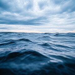 Fototapeta premium Dark blue ocean waves under a cloudy sky.