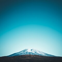 Snow-capped mountain peak against a vibrant blue sky.