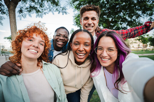 Group of happy teenagers smiling and having fun outdoors, enjoying friendship and diversity while taking a selfie together in a park on a bright sunny day. Young friends smiling and laughing