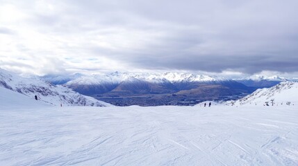 Obraz premium A snowy mountain landscape with skiers and a scenic view of the valley below.