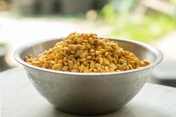 A big bowl of soaked soybean isolated on white table in kitchen selective focus blur background closed up. Prepare to make soymilk (soybean milk or hoya milk)