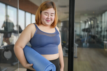 Obese asian woman diet holding yoga mat for training yoga exercising fitness workout and health concept. training working out at gym