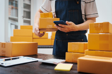 Close-up of a businessman’s hand packing items at a desk, preparing products for shipping....