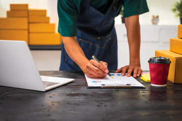 Close-up of a businessman’s hand packing items at a desk, preparing products for shipping. Highlighting delivery services for private companies online shopping with credit cards for convenience
