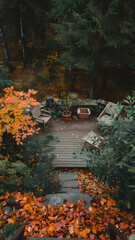 High-angle view of a wooden deck in an autumnal garden setting.  Surrounding the deck are fall leaves, potted plants, and wooden chairs.  A stone pathway leads down from the deck.